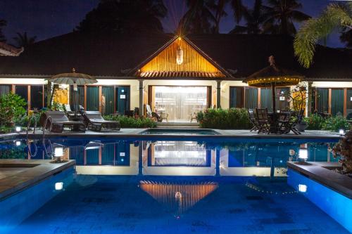 a house with a swimming pool at night at Villa Gusmania in Candidasa