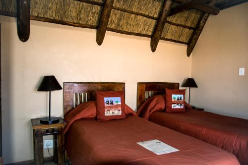 two beds in a room with wooden ceilings at Xaus Lodge in Twee Rivieren