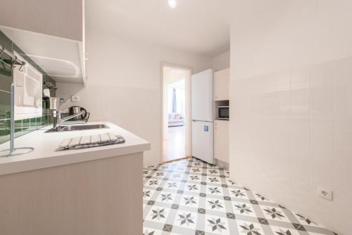 a white kitchen with a black and white tile floor at Assuncao Apartment in Lisbon