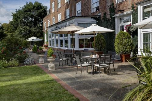 a patio with a table and chairs and umbrellas at Best Western Homestead Court Hotel in Welwyn Garden City