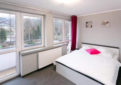 a bedroom with a white bed and two windows at Pokoje Beskid Brenna in Brenna