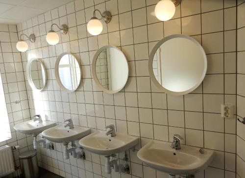 a bathroom with three sinks and three mirrors at Go to sleep Arvika in Arvika