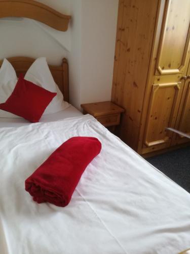 a white bed with two red pillows on it at Gasthof Platzschmied in Guttaring