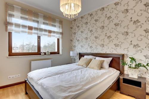 sypialnia z dużym łóżkiem i żyrandolem w obiekcie Seaside with Sunny Terrace w Gdańsku