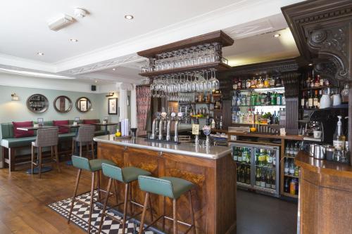 a bar in a restaurant with bar stools at The Stratford Townhouse in Stratford-upon-Avon