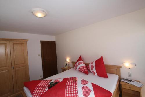 a bedroom with a bed with red and white pillows at Pfandlhof in Walchsee