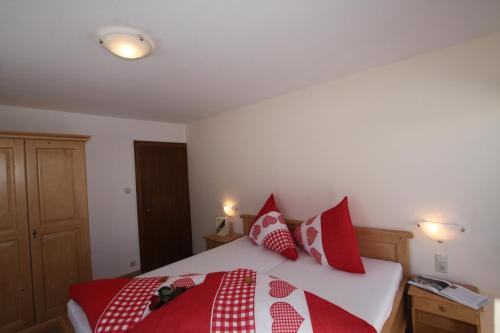 a bedroom with a bed with red and white pillows at Pfandlhof in Walchsee