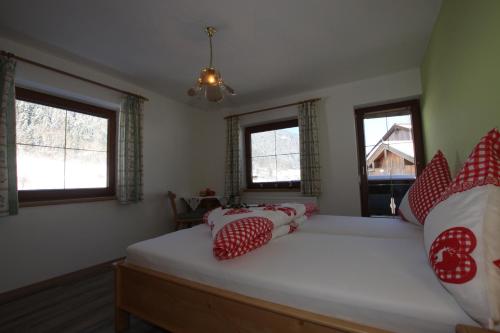a bedroom with a large bed with red and white pillows at Pfandlhof in Walchsee