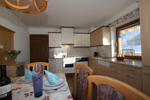 a kitchen with a table and chairs and a kitchen with white cabinets at Pfandlhof in Walchsee