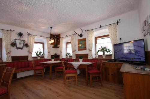a dining room with tables and chairs and a flat screen tv at Pfandlhof in Walchsee