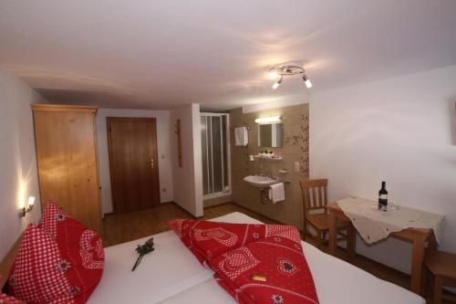 a bedroom with a bed with red pillows and a table at Pfandlhof in Walchsee