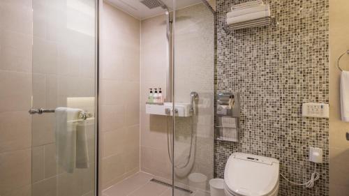 a bathroom with a toilet and a glass shower at First Stay Hotel in Seoul
