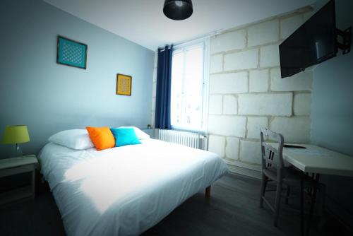 a bedroom with a bed and a desk and a window at Hotel de la gare in Château-du-Loir