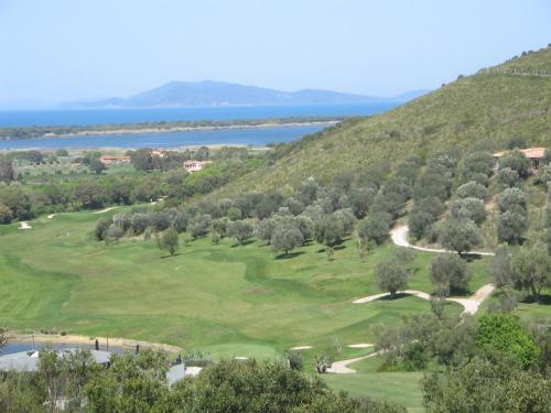 a view of a golf course with the ocean in the background at Country Relais La Mortella in Porto Ercole