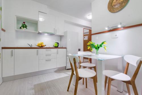 a kitchen with white cabinets and a table and chairs at Vila Marija in Skradin