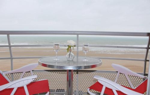 a table with two wine glasses and a flower on a balcony at Apartment "Zeezicht" in Ostend