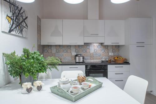 a kitchen with white cabinets and a white table at La Gazza Ladra Apartments - Garda Chill Out in Drena
