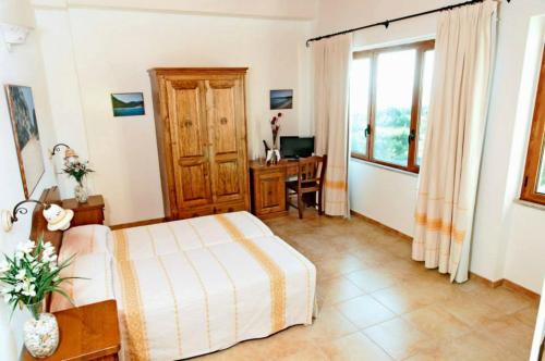 1 dormitorio con cama, escritorio y ventana en Bellamarina, en Sorso