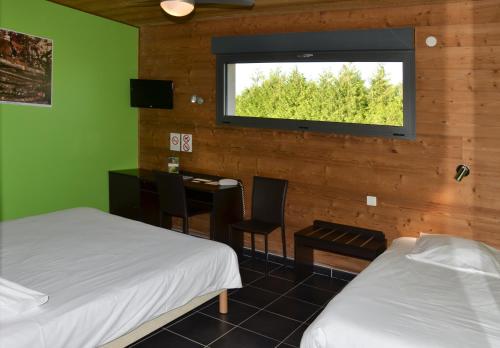Habitación con 2 camas, escritorio y ventana. en Bio Motel, en Semoutiers