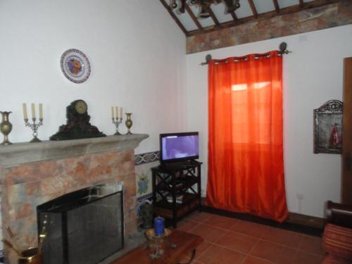 a living room with a fireplace and a red curtain at Casa do Rei in Furnas