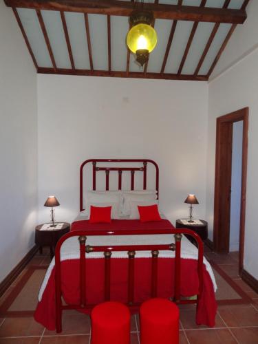 a bedroom with a red bed with two red chairs at Casa do Rei in Furnas