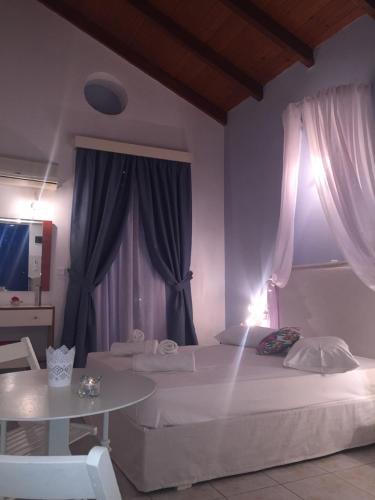 a bedroom with a white bed and a table and curtains at Dreams Apartments - Katelios,Santa Barbara beach in Katelios