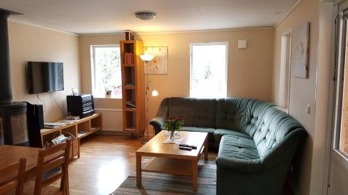 ein Wohnzimmer mit einem grünen Sofa und einem Couchtisch in der Unterkunft Modal Annex in Hultsfred