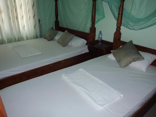 two twin beds in a room withthritisthritisthritisthritisthritisthritisthritisthritisthritis at Rock Villa Relax City Resort in Mihintale