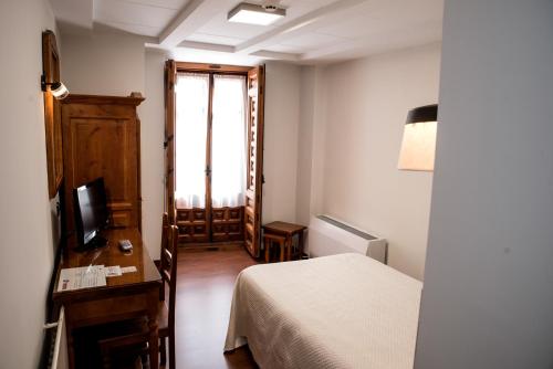 a bedroom with a bed and a television and a window at Hotel Santa Isabel in Toledo