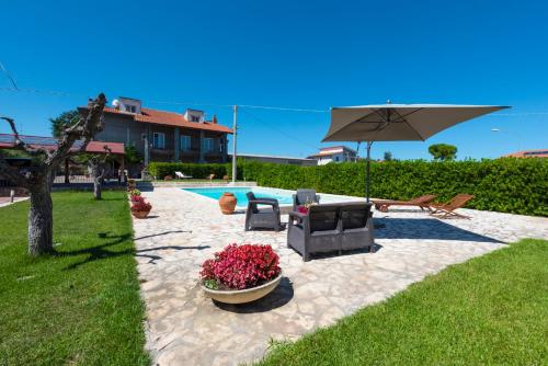 une terrasse avec une télévision, un parasol et des fleurs dans l'établissement Villa Miranda, à Ortona