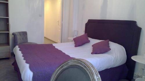 a bedroom with a large bed with purple pillows at Hotel De La Bastide in Carcassonne