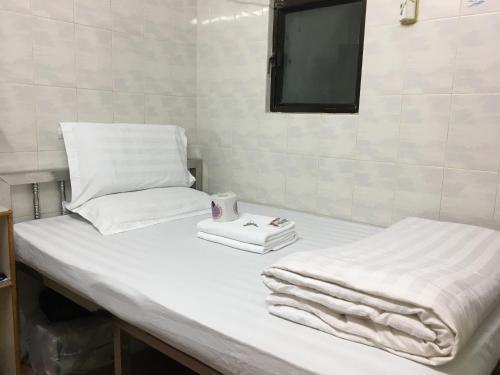 1 cama blanca con toallas y TV. en New Yan Yan Guest House reception 9th floor Flat E4 E6 en Hong Kong