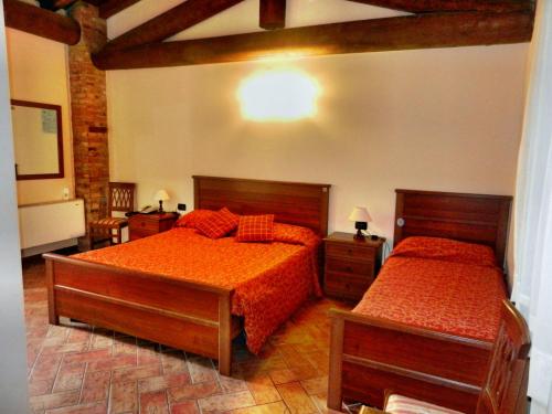 a bedroom with two beds with orange sheets and wooden floors at Agriturismo SANGALLO in bedizzol