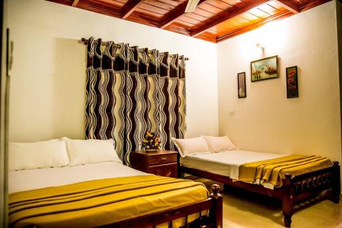 a room with two beds and a window with a curtain at Elroy Homestay in Kalpetta