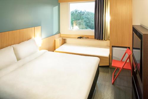um pequeno quarto com 2 camas e uma janela em ibis Rio de Janeiro Parque Olimpico no Rio de Janeiro