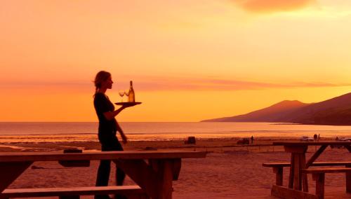 a woman standing on the beach with a tray of food at Inch Beach House B&B in Inch