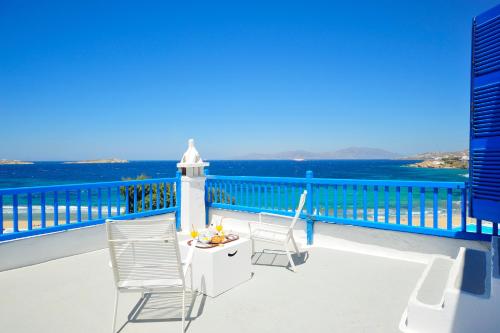 a balcony with two chairs and a table and a lighthouse at Mykonos Beach Hotel in Mýkonos City