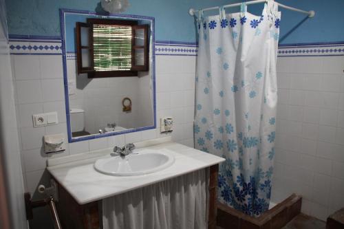 a bathroom with a sink and a shower curtain at Casa Rural Casa Ronda in El Bosque