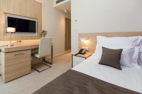 a hotel room with a bed and a desk with a computer at Hotel Crikvenica in Crikvenica