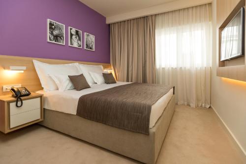 ツリクヴェニツァにあるHotel Crikvenicaの紫の壁のベッドルーム1室(大型ベッド1台付)