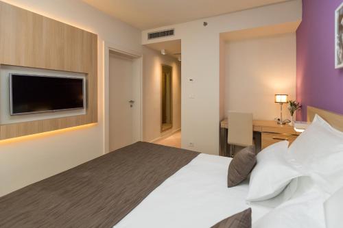 a bedroom with a bed and a desk and a tv at Hotel Crikvenica in Crikvenica