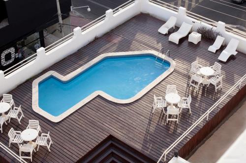 a swimming pool on top of a roof with tables and chairs at JB Hotel in Petrolina