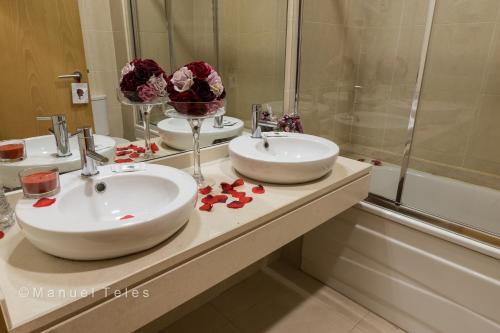 a bathroom with two sinks and a mirror at Hotel Tulipa in Bragança