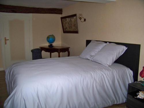Un dormitorio con una cama blanca y una mesa. en Gite De La Tour De Rouilleres, en Ambierle