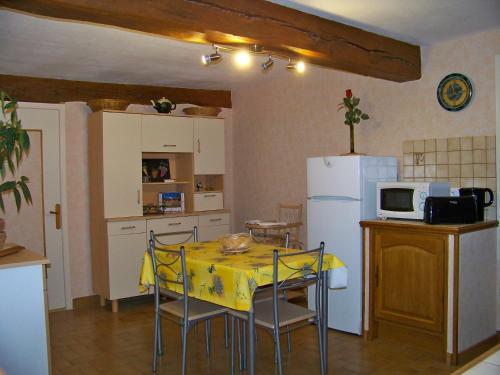 a kitchen with a table and a white refrigerator at Gite De La Tour De Rouilleres in Ambierle