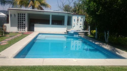 a blue swimming pool in front of a house at Quinta Belu Oaxtepec in Oaxtepec