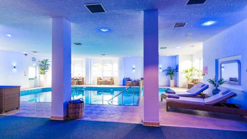 a swimming pool with chairs and a couch in a room at The Royal Duchy Hotel in Falmouth