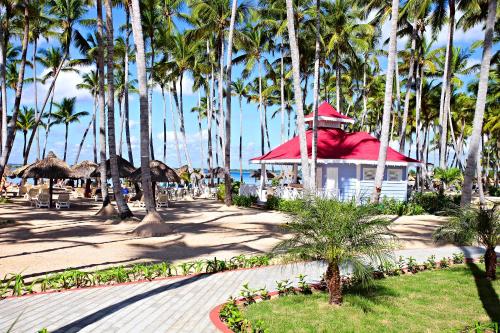 a beach with palm trees and a building with a red roof at Bahia Principe Grand La Romana - All Inclusive in La Romana