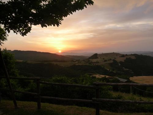 a sunset over the hills with a fence in the foreground at Agriturismo Girolomoni - Locanda in Isola del Piano