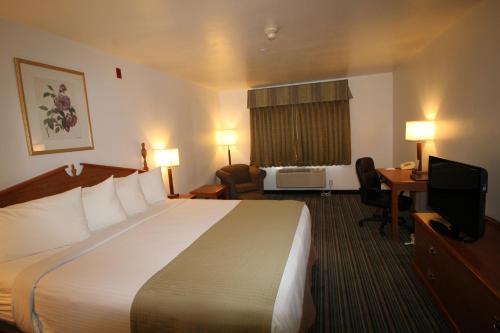 a hotel room with a bed and a desk and a television at Best Western Liberty Inn in Delano